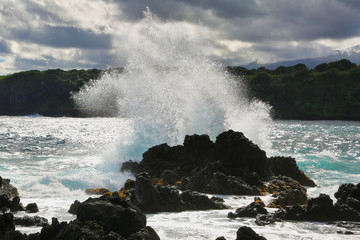 Wave crashes on rocks tropical beach