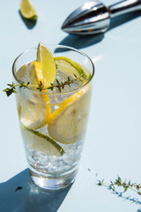Lemonade or mojito cocktail with lemon and lime, cold refreshing drink or beverage with ice on a light blue backround. Retro style with artistic trendy shadows.