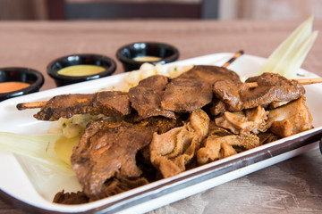 Traditional Peruvian food 'Anticuchos' grilled skewered beef heart meat cooked on barbecue grill