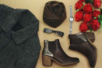 Set of women's autumn, winter clothes:  coat, brown boots and bouquet of flowers, eyeglasses and brown scarf, hand watch. Fashionable clothes for walks, flat lay