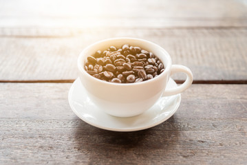 Coffee beans in a mug on a wooden table.