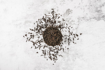 Dried tea is poured into a white ceramic cup on a marble table. View from above. Layout.