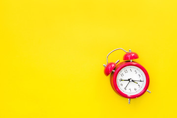 Red vintage alarm clock on a yellow background, top view