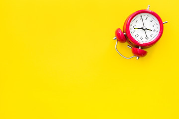 Red vintage alarm clock on a yellow background, top view