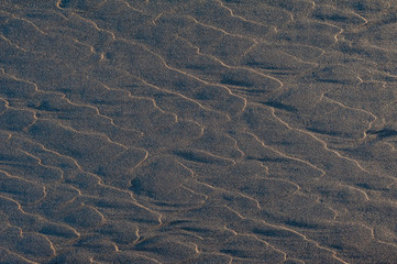 Black volcanic sand waves abstract background texture with copyspace. Black beaches of Iceland.
