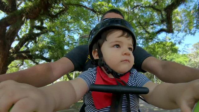 Father with baby riding a bicycle in the park. Ibirapuera park in Sao Paulo city. 4K 60fps.