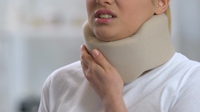 Woman in foam cervical collar feeling neck pain after trauma, rehabilitation