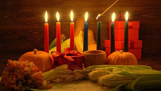 Kwanzaa holiday concept with ignite seven candles red, black and green, corns, grapes, bananas, gift boxes, pumpkin, bowl and fruits