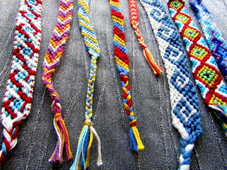 Woven friendship bracelets of threads with tassels on a gray background