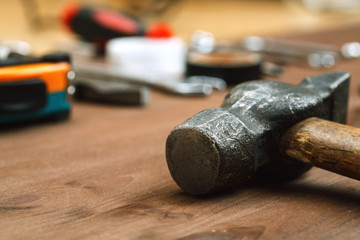 Massive hammer with other tools on a wooden table in workshop