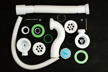 Parts of sink drain kit on a black background, top view, Plumbing concept.