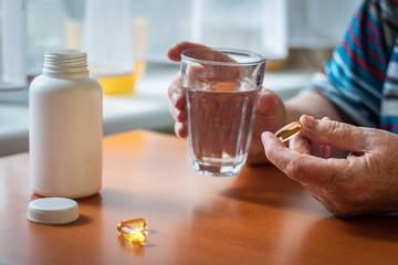 Senior woman is taking omega-3 medicine capsule