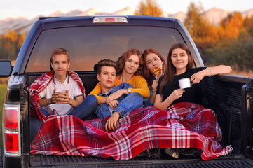 Girls and boys in a pickup car rest in nature