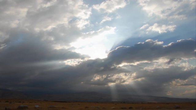 Sunbeams stream through time lapse storm clouds.