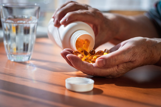 Senior Woman Taking Omega 3 Pills From Bottle. Medical Concept