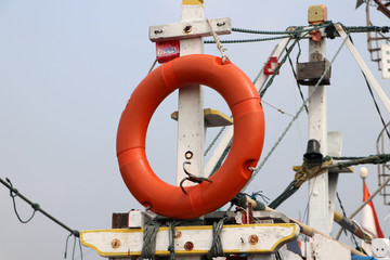 Safety life ring hanging on fishing boat masts.