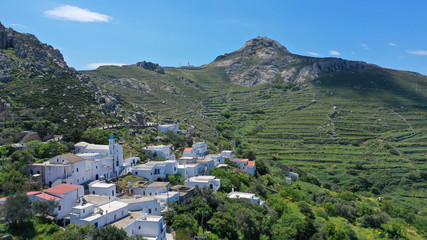 Fototapeta na wymiar Aerial drone photo of picturesque traditional village of Koumaros in the slopes of mountain and castle of Exomvourgo or Exombourgo with beautiful deep blue sky, Tinos island, Cyclades, Greece