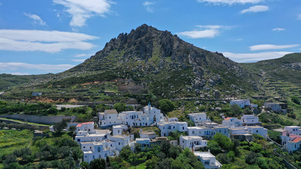 Aerial drone photo of picturesque traditional village of Koumaros in the slopes of mountain and castle of Exomvourgo or Exombourgo with beautiful deep blue sky, Tinos island, Cyclades, Greece