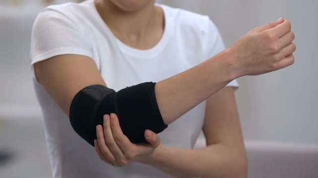 Female wearing elbow padded orthosis on painful joint, orthopedic support