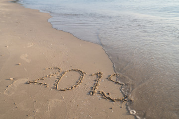 Lettering on beach with wave wiping year 2019 ends prepare to 2020 for new year celebrate