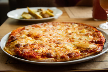 Big cheese pizza on the table in the restaurant.