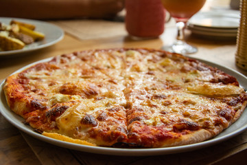 Big cheese pizza on the table in the restaurant.