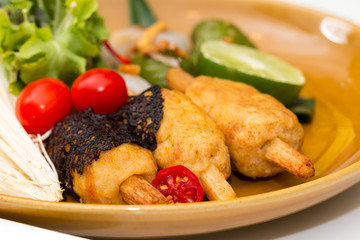 Close up of crispy shrimp wrapped with sugar cane decorated by tomaot and vegetable