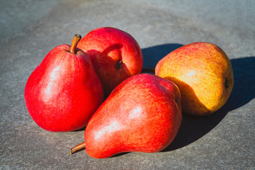 Ripe red pears on the background of a stone table top close-up.