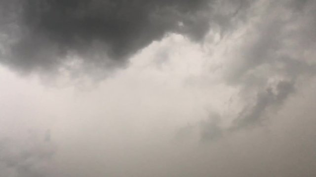 Lightning flashes from a dark cloud during a thunderstorm. Cloudy weather, rain. The video is looped.
