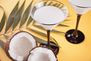 Pina Colada cocktail on the yellow table with palm leaf and coconut on the background