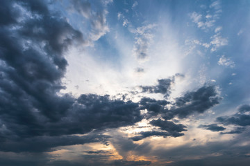Sunset behind dark grey clouds on sky