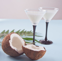 Pina Colada cocktail on the blue table with palm leaf and coconut on the background