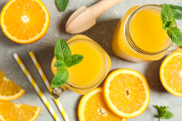 Composition with orange pieces, mint, tubules, wooden juicer and glass jars with fresh orange juice...