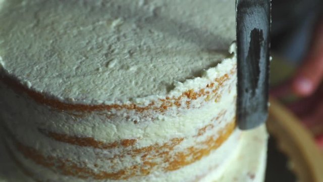 Close up of applying white cream on top of cake during preparation and decorating a corpus for a wedding cake in close up
