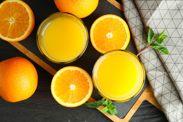 Cutting board with orange juice, mint and oranges and kitchen towel on wooden background, top view....