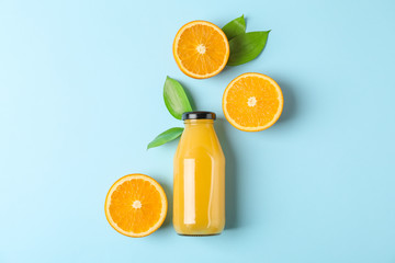 Flat lay composition with fresh orange juice in bottle and oranges with leaves on color background,...