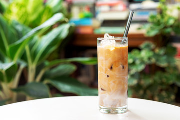 a glass of iced latte coffee with reusable glass straw on white table, eco friendly zero waste living concept..