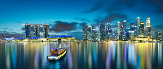 Panorama view of Singapore city skyline with tourist boat at night . Travel asia concept .