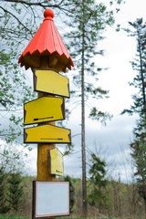 Conceptual blank signs of yellow color in forest - red roof