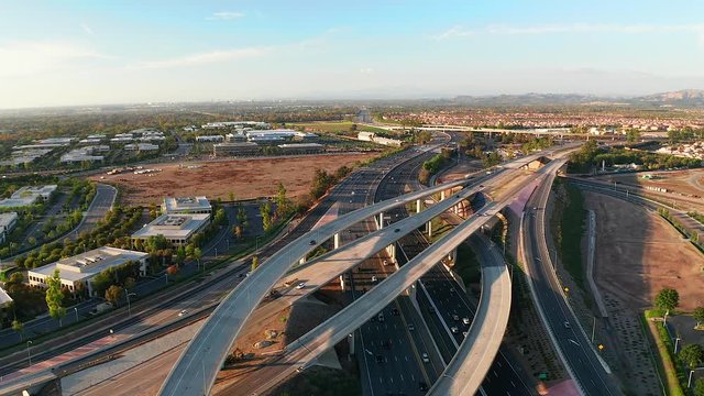 Aerial view drone shot above a busy freeway or interstate with cars rushing below on a blue sky day.