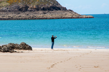 man on the beach takes pictures on the phone