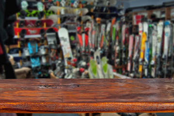 Mockup. Image of sport store with equipment for skiing. Defocused, blurred image. In the foreground is the top of a wooden table, counter.