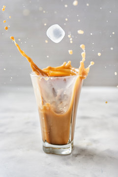 Iced Coffee With Splash On Glass Over Grey Background