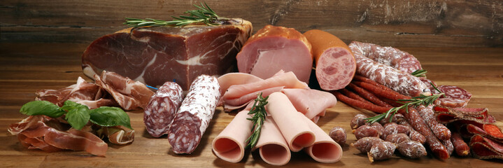 cold meat assortment with delicious salami and  fresh herbs . Variety of meat products including...