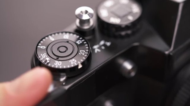A young photographer changes settings of a vintage Soviet film camera, focuses and takes a picture. Close-up.