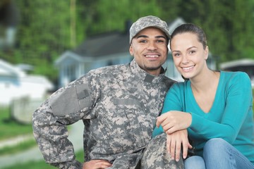 Fototapeta na wymiar Smiling soldier with his wife standing against background
