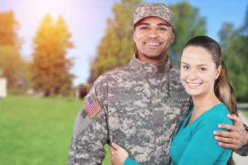 Smiling soldier with his wife standing against  background