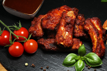 Spicy hot grilled spare ribs from a summer BBQ served with fresh tomatoes on an vintage cutting board