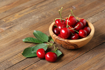 ripe cherries in a wooden bowl on a wooden table