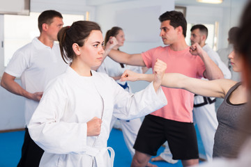 Fototapeta na wymiar Young males and females are practicing new karate moves in pairs